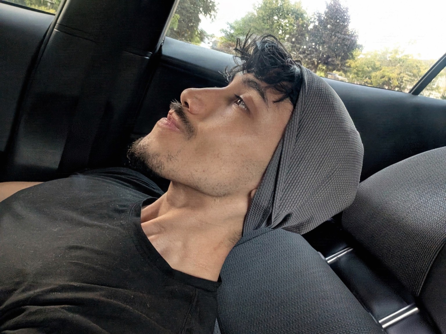 Giancarloue in profile, wearing a hood while seated in a car.
